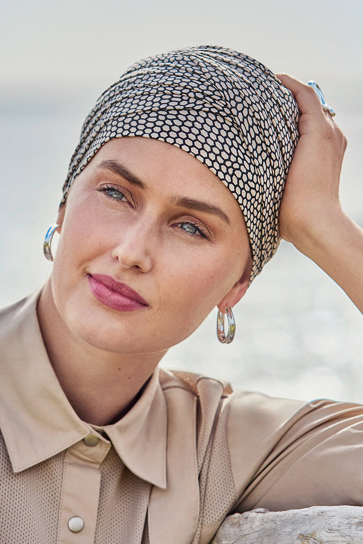 Woman wearing a patterned headscarf outdoors with a blurred natural background