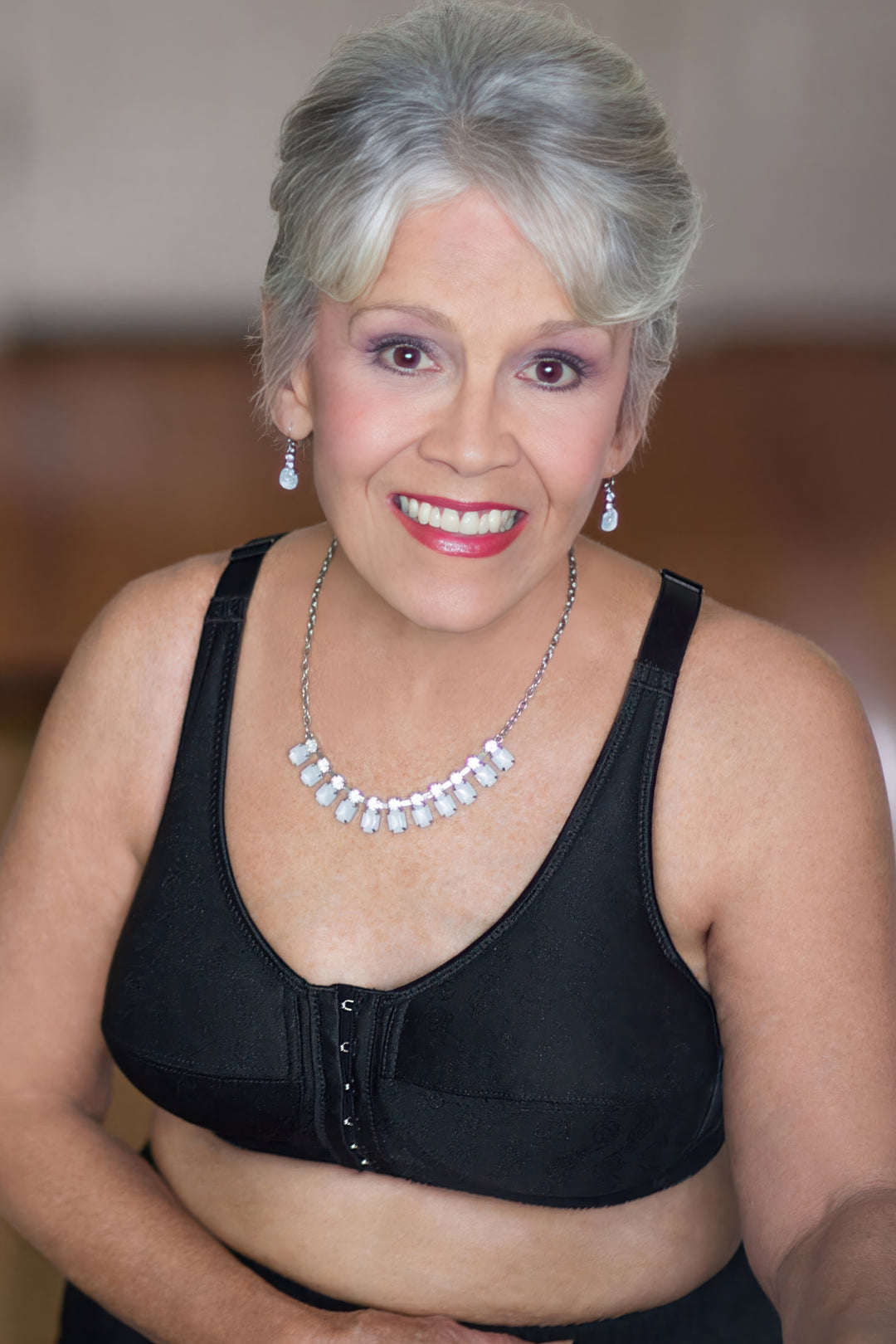 Woman wearing a black mastectomy bra with jewelry against a blurred background