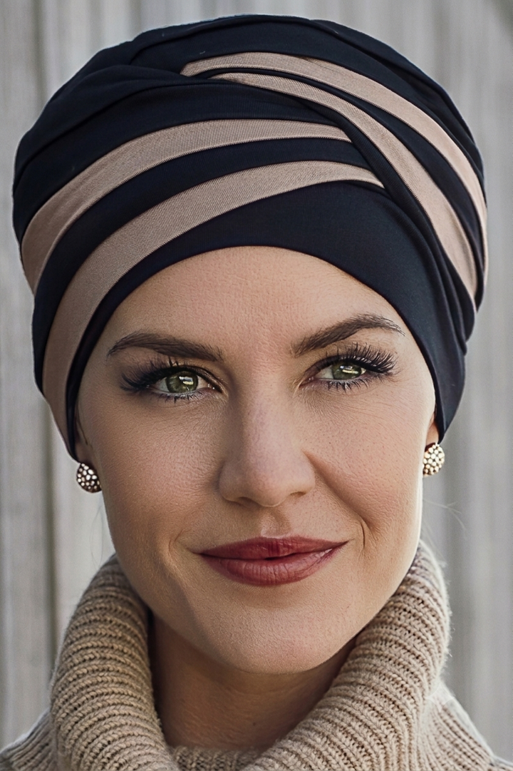 Woman wearing a black and beige striped hair loss turban with a neutral background